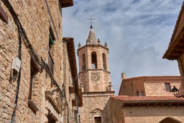 Cantavieja 'daki Varsayım Kilisesi ortaçağ ruhunu koruyan bir grup taş binanın üzerinde yükselir. Duvarların ve tavanların ılık tonları parçalı bulutlu gökyüzü ile tezat oluşturuyor.