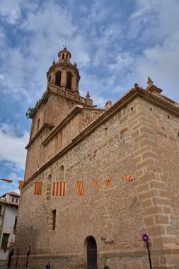 Rubielos de Mora 'daki eski Santa Maria Belediye Başkanı heybetli kolej kilisesi, sıcak tonlu çan kulesi ve kubbesi, bazıları serpiştirilmiş bulutlar arasında değişen bir gökyüzü altında, kiremit ya da mavi-yeşil fayans detaylarıyla görkemli bir şekilde yükselir.