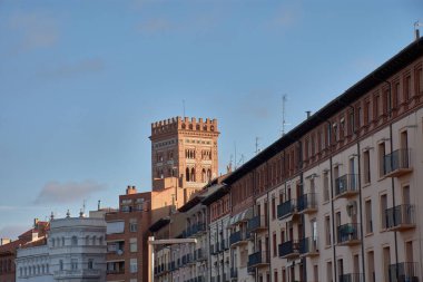San Martin 'in görkemli Mudejar Kulesi, tanınmış bir Dünya Mirası Alanı, belirgin kırmızımsı tuğla yapısı, ayrıntılı geometrik kafes kalıpları, yeşil ve beyaz fayanslar ve birden fazla kemer ve pencere ile görkemli bir şekilde yükselir.. 