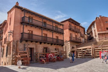 Albarakin, İspanya - 6 Eylül 2025, Albarakin kasabasında dar ve sık sık dik bir cadde, kırmızı ve koyu renkli cepheleriyle karakterize edilen geleneksel evler arasında, ahşap ve işlenmiş demir balkonlarla yükselir.. 