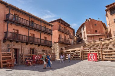 Albarakin, İspanya - 6 Eylül 2025, Albarakin kasabasında dar ve sık sık dik bir cadde, kırmızı ve koyu renkli cepheleriyle karakterize edilen geleneksel evler arasında, ahşap ve işlenmiş demir balkonlarla yükselir.. 