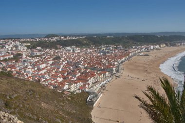 From a high vantage point, O Sitio, you can see Nazare beach stretching out along the ocean, with red roofs contrasting with the golden sand and blue sea. 