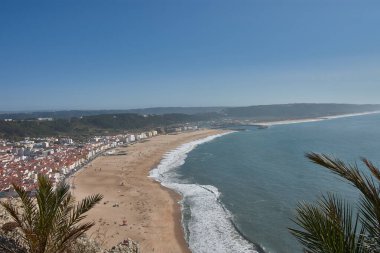 From a high vantage point, O Sitio, you can see Nazare beach stretching out along the ocean, with red roofs contrasting with the golden sand and blue sea. 