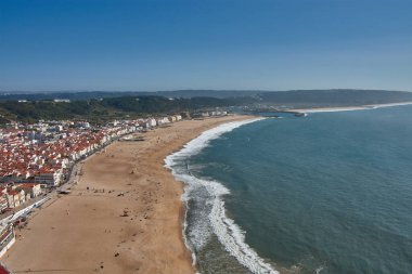 From a high vantage point, O Sitio, you can see Nazare beach stretching out along the ocean, with red roofs contrasting with the golden sand and blue sea. 