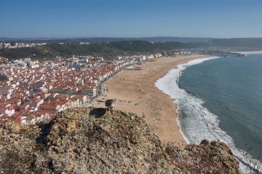 From a high vantage point, O Sitio, you can see Nazare beach stretching out along the ocean, with red roofs contrasting with the golden sand and blue sea. 