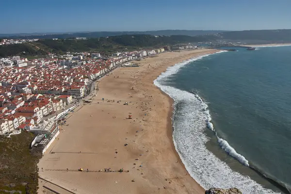 From a high vantage point, O Sitio, you can see Nazare beach stretching out along the ocean, with red roofs contrasting with the golden sand and blue sea. 
