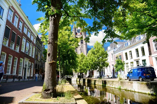 24.07.2024. Hollanda 'da. Delft. Fotoğraf, Delft şehrinde Oude Kilisesi 'nin eğimli kulesine bakan bir sokak ve kanal gösteriyor..