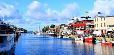 Warnemuende, Almanya - 11 Ekim 2024 - Fotoğrafta deniz kıyısındaki Warnemuende tatil beldesinde tekneli bir kanal görülüyor. Rostock ilçesinin bir ilçesidir..