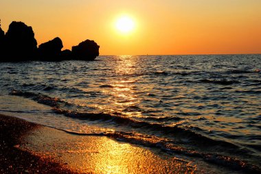 Kayalık bir sahilde gün batımı.