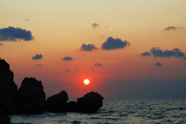 Deniz kıyısında. Taşlar. Denizin üzerinde güzel bir gün batımı.