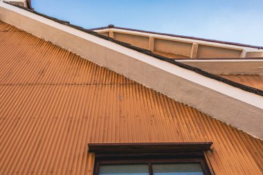 Pencere Çerçevesinin Kısmi Görünümüne sahip Turuncu Renkli Metal Panelli Binanın Dış Görünümü