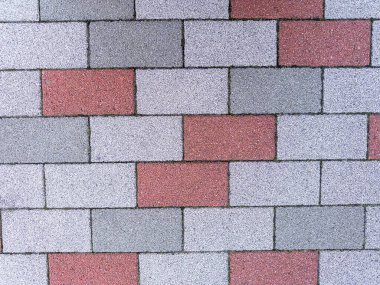 Sönük beyaz, gri ve açık mercan somon pembe renkli granül kaplama kaldırım taşları sersemletici şekillerde serili..