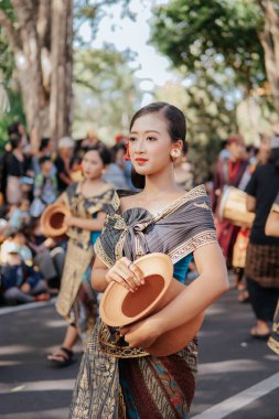 Denpasar, Endonezya - 12 Haziran 2023: Bali Sanat Festivali 'nin açılış töreninde vazo taşıyan genç bir kadın.