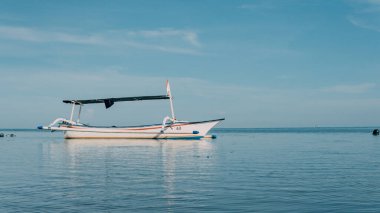 Mavi Gök 'ün altında sakin bir denizin ortasında boşta duran bir balıkçı kanosu..
