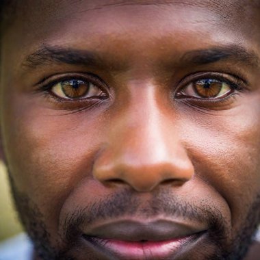 Extreme macro shot of an African man, captured with a soft focus and eye-level perspective. The portrait highlights the subtle details and emotions. Photo-realistic. clipart