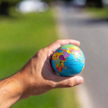 A person is holding a small globe in their hands, displaying the Earths clipart