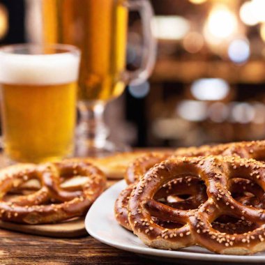 extreme macro photo of a platter of pretzels and sausages, with a shallow focus on the coarse salt and grill marks, set against the blurred image of Oktoberfest beer steins in the background clipart