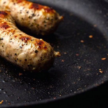 close-up macro image of a juicy sausage sizzling on a skillet, with the studio lighting emphasizing the texture and steam, captured from a low angle with a soft focus to give a dreamy feel clipart