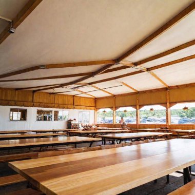 An eye-level shot of an Oktoberfest beer tent interior, focusing on the traditional wooden tables and benches, with the lively atmosphere of the tent softly fading into the background clipart