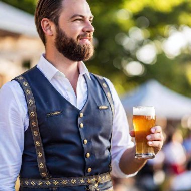 young man in a traditional bavarian costume holding a mug of beer in the oktoberfest clipart