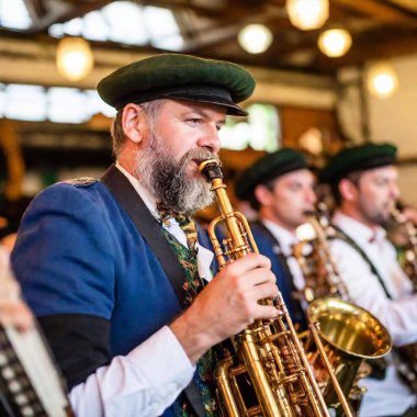 Münih Oktoberfest 'te bir bira çadırında çalan Bavyeralı bir grubun yakın plan görüntüsü. Müzisyenlerin enstrümanlarından hareketle dans eden ve müziğin tadını çıkaran enerjik kalabalığa yöneldiler..