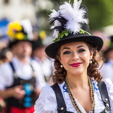 Münih Oktoberfest geçit töreninde bandosuyla bavyera şapkalı aşırı makro portredeki kadın. Şenlik arka planı göz hizasında bulanıklaşan raf odağı.