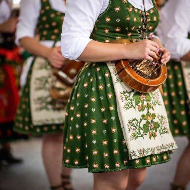 Extreme macro shot of a traditional Bavarian folk music group on stage, with a rack focus transitioning to the vibrant patterns of the musicians lederhosen and dirndls. The crowd in the background is slightly blurred, emphasizing the musicians attire clipart