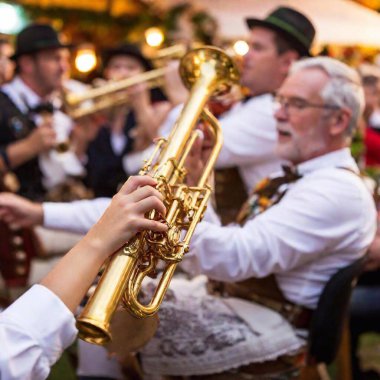 Aşırı makro çekim, Oktoberfest 'te Bavyeralı bir folk müzik grubunun enerjisini yakalıyor. Çadır ışıklarının altında parlayan trompetin çanına yakından odaklanıyor. Orkestra ve kalabalık hafif bulanık, enstrümanı vurguluyorlar..