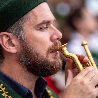 Extreme macro shot of the lips of a Caucasian male musician as he blows into a traditional Bavarian trumpet at Oktoberfest. The details of the lips and the trumpet mouthpiece are sharp, while the rest of his face fades softly into the background clipart