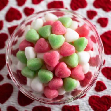 A retro-themed extreme macro shot from above of a glass bowl filled with heart-shaped candies. The deep focus allows every candy and the surrounding retro-patterned tablecloth to be captured in sharp detail clipart