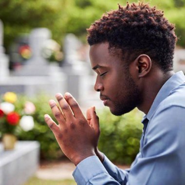 Whispered Prayers, close-up of young black man with his eyes closed in prayer at a cemetery, dark tones of his profile contrasting with vibrant offerings nearby clipart