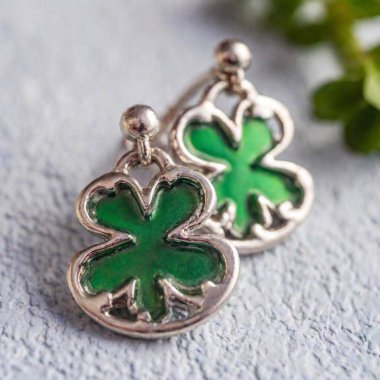 Medium Close-Up, Shallow Focus, Eye Level Shot: A pair of Shamrock earrings crafted from sterling silver, with a subtle Celtic knot design interwoven into each leaf. clipart