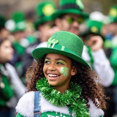 A festive street scene during St. Patrick Day, with people of all ages wearing green accessories like hats, scarves, and face paint, creating a sea of green. clipart