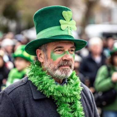 A festive street ground level scene during St. Patrick Day, with people of all ages wearing green accessories like hats, scarves, and face paint, creating a sea of green. clipart