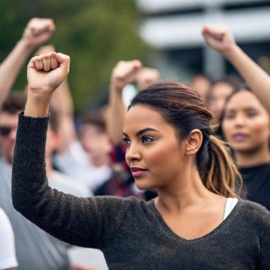 A close up image of women raising their fists in the air during a rally, with a focus on their strong, determined faces and the intensity of their collective voice demanding change. clipart