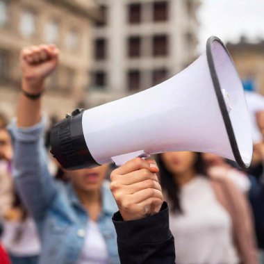 A close-up of a woman hand gripping a megaphone as she leads a chant during a protest, with other women rallying behind her, capturing the energy and urgency of the movement. clipart