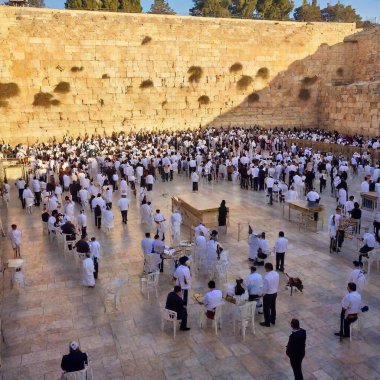 A Yom Kippur gathering at the Western Wall, with people praying as the sun sets, the ancient stones glowing softly in the golden light, creating a serene and spiritual scene clipart