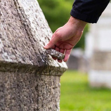 a man's hand places a small stone on a Jewish grave clipart