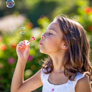 cute little girl blowing soap bubbles in the park clipart