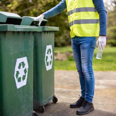 Close-up shot of a volunteer placing a bottle into a recycling bin during an Earth Day cleanup, with the bottle in sharp focus and the bin softly fading into the background, showcasing responsible waste management clipart