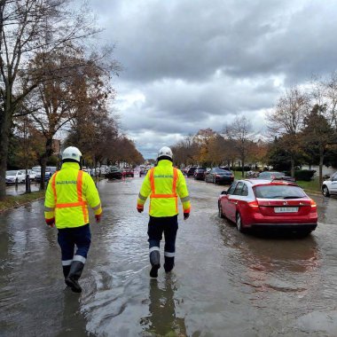 first responder's view of a flood scene on a city road with cars and rescue workers clipart