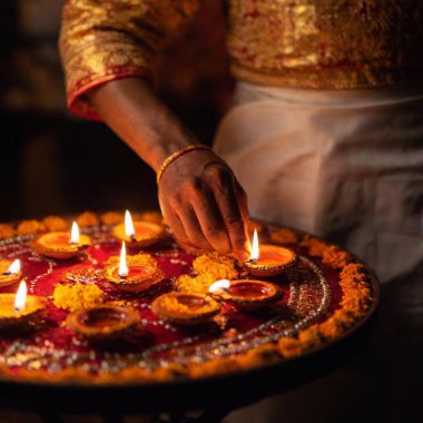 Design a full shot of a male adult engaged in Diwali prayers, with an over-the-shoulder perspective and shallow focus, drawing attention to the diya lamps and prayer thali in the foreground while the rest of the scene remains softly blurred clipart