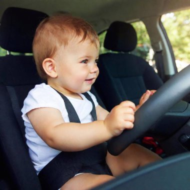 baby boy sitting in car with steering wheel clipart