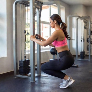 A woman doing lat pulldowns on a machine clipart