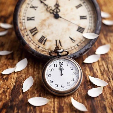 Create a photorealistic 16x9 image featuring a close-up of delicate flower petals scattered around an antique clock or pocket watch atop a table with a glimpse of the English country side in the distance clipart