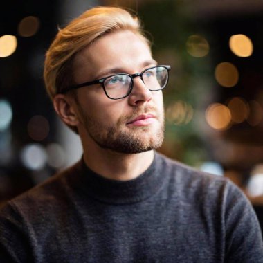 portrait of a handsome young man in glasses in a dark room clipart