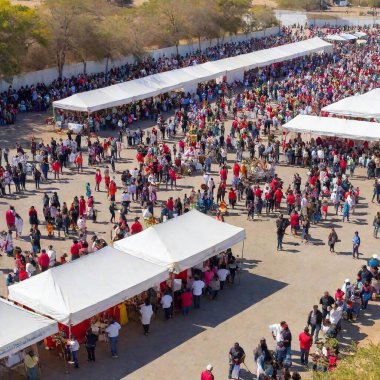 A comprehensive wide shot of the religious ceremonies held at a major outdoor venue for Virgin of Guadalupe Day, displaying the large scale of the event with numerous tents, altars, and participants clipart