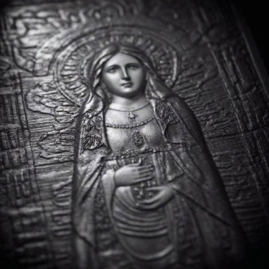 An extreme close-up flatlay of a Virgin of Guadalupe Day prayer card or religious text, rendered in noir with high contrast and shadow play, emphasizing the textures and intricate details clipart