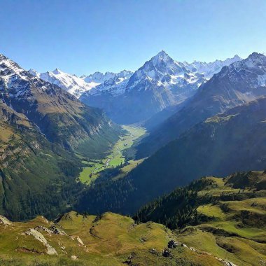 A full shot of a picturesque mountain range viewed from a high angle. The photograph captures the rugged peaks and rolling valleys, with snow-capped summits and lush green valleys extending far into the distance, under a bright and cloudless sky. clipart