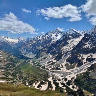 A full shot of a picturesque mountain range viewed from a high angle. The photograph captures the rugged peaks and rolling valleys, with snow-capped summits and lush green valleys extending far into the distance, under a bright and cloudless sky. clipart